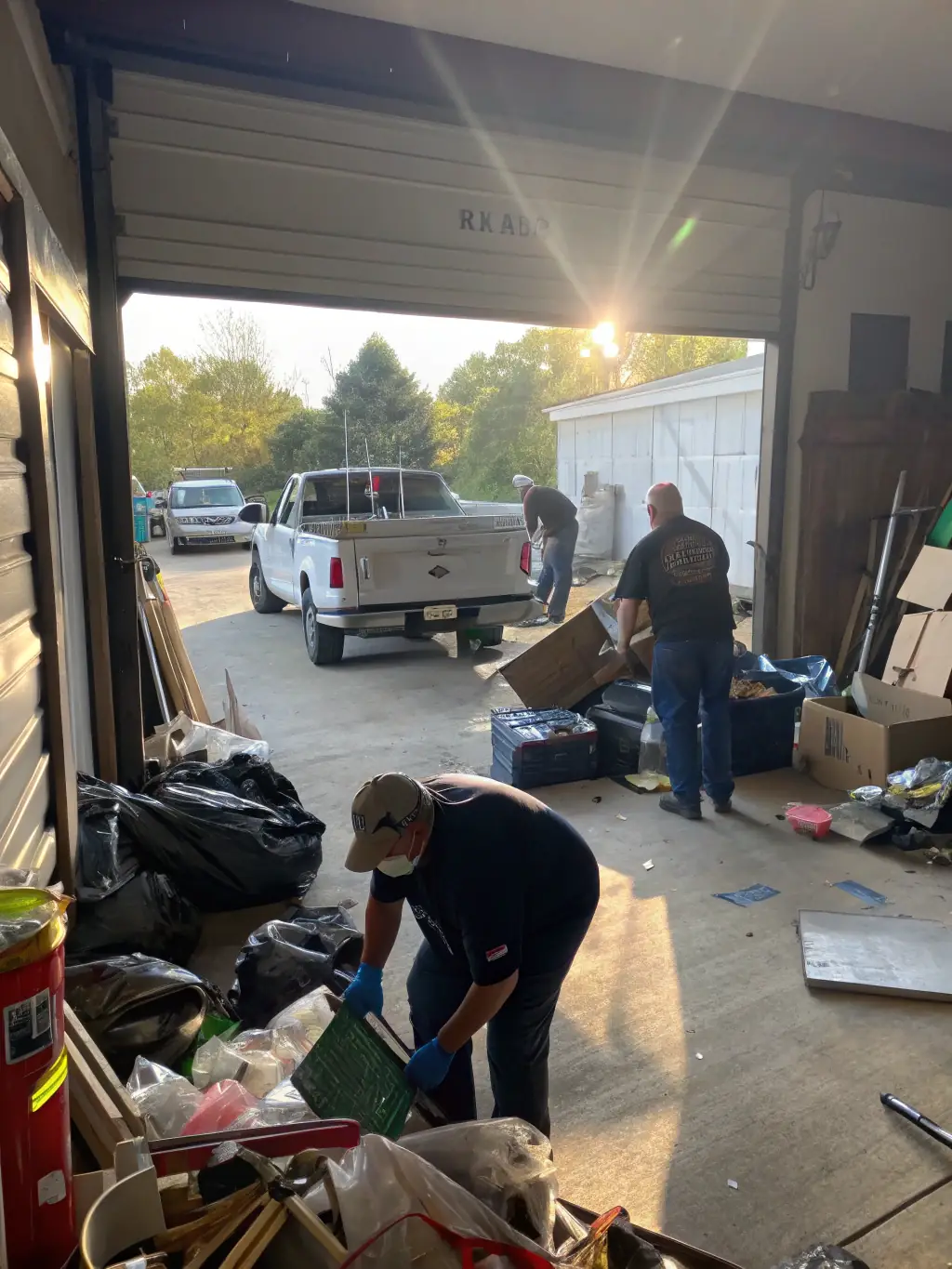 A Junk Junkies Texas team cleaning out a cluttered garage, organizing items for disposal and recycling.